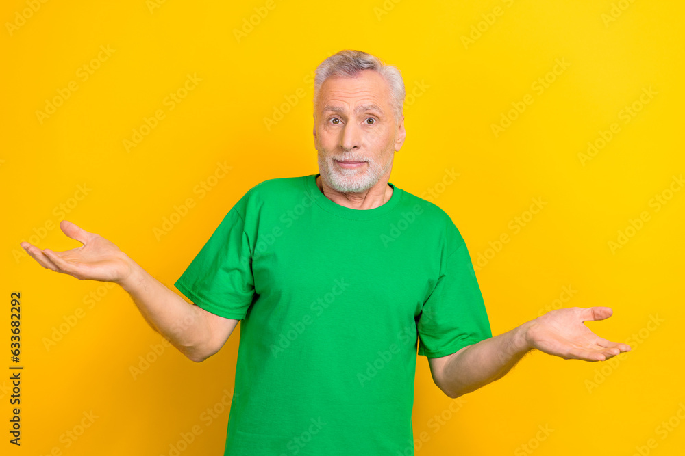 Photo of funny unsure guy dressed green t-shirt shrugging shoulders isolated yellow color background Photo of funny unsure guy dressed green t-shirt shrugging shoulders isolated yellow color background