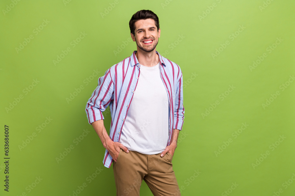 Portrait of satisfied handsome nice man with brunet hair wear stylish clothes hold hands in pockets isolated on green color background Portrait of satisfied handsome nice man with brunet hair wear stylish clothes hold hands in pockets isolated on green color background
