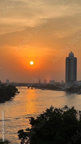 Aerial view of boat traffic on Chao Praya river with sunset, skyscrapers along Chao Praya river during sunset.