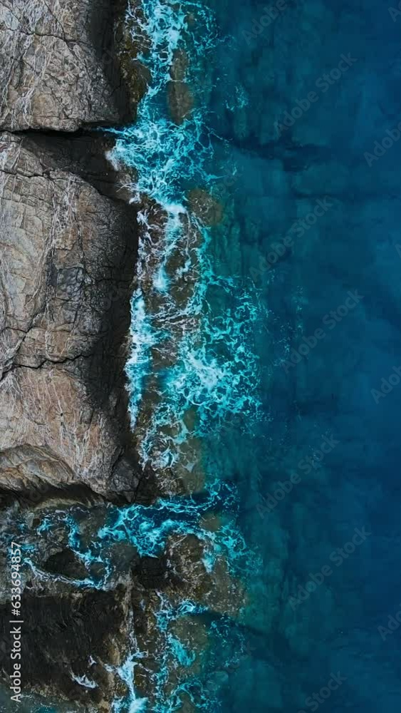 Cliffs of Aegean sea coast, drone aerial view of waves crashing rocks. vertical social media Cliffs of Aegean sea coast, drone aerial view of waves crashing rocks. vertical social media