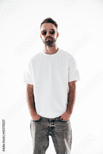 Portrait of handsome smiling stylish hipster lambersexual model. Sexy man dressed in white T-shirt and jeans. Fashion male isolated on white background in studio