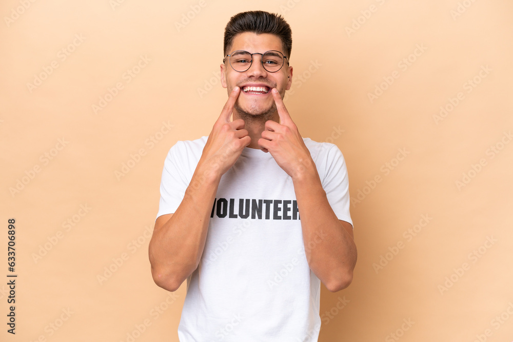 Young volunteer caucasian man isolated on beige background smiling with a happy and pleasant expression Young volunteer caucasian man isolated on beige background smiling with a happy and pleasant expression