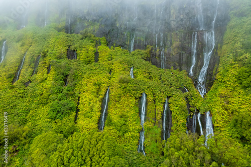 Azores scenic aerial drone landscape, Flores island. Iconic lagoon with several waterfalls on a single rockface, flowing into lake Alagoinha. Best travel destination in Portugal.