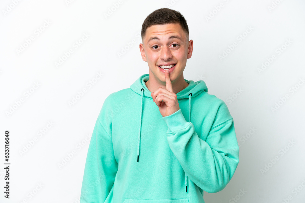 Young brazilian man isolated on white background showing a sign of silence gesture putting finger in mouth