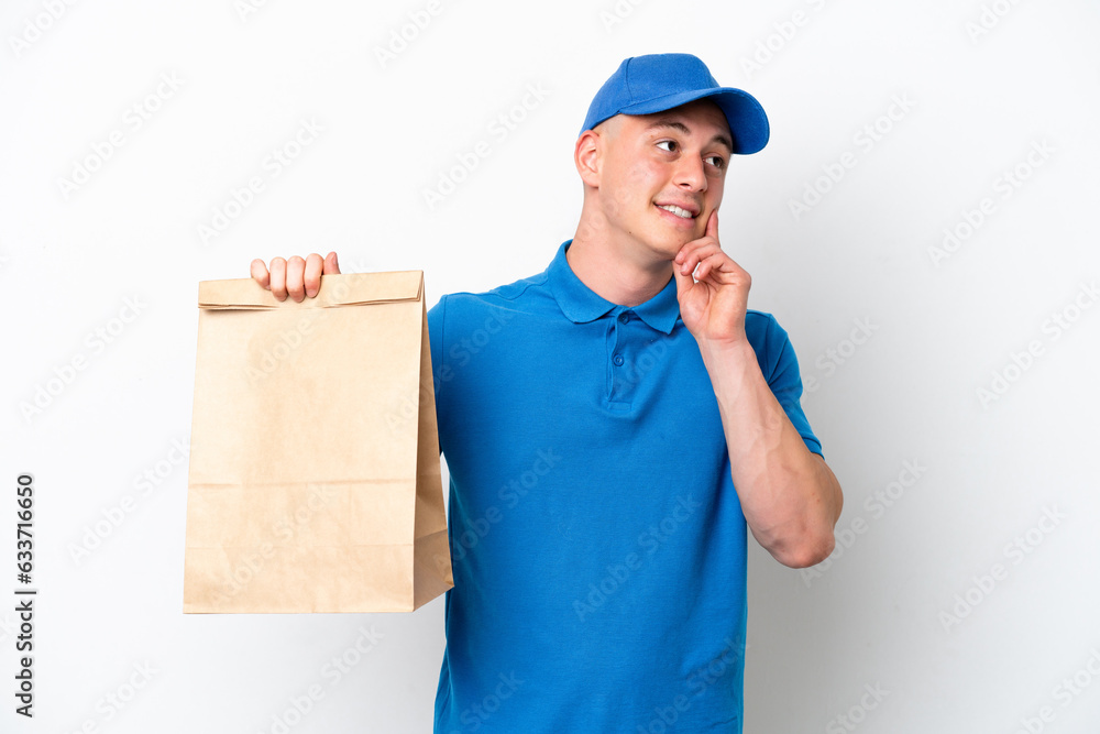 Young Brazilian man taking a bag of takeaway food isolated on white background thinking an idea while looking up Young Brazilian man taking a bag of takeaway food isolated on white background thinking an idea while looking up