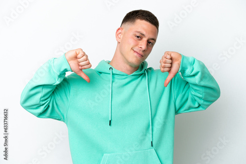 Young brazilian man isolated on white background showing thumb down with two hands © luismolinero