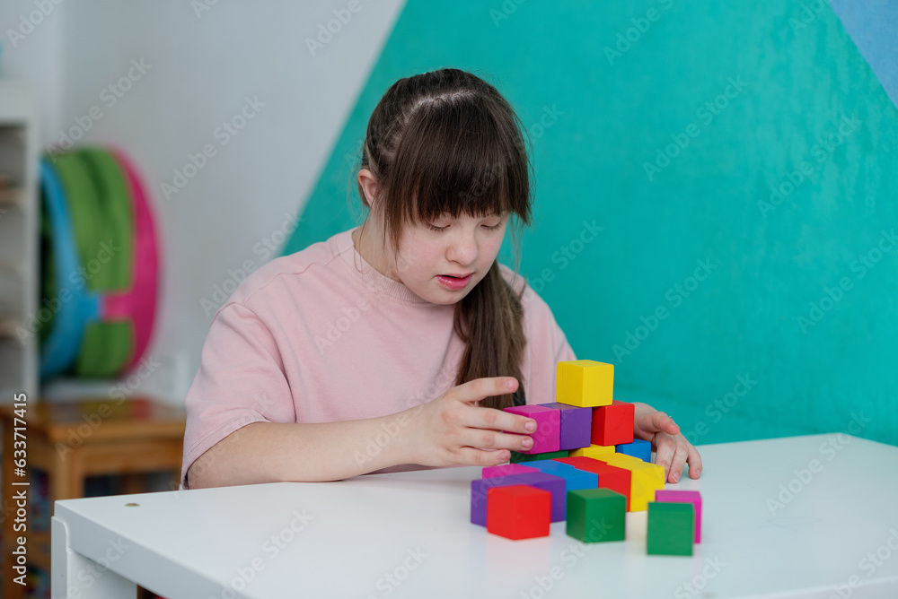 Sunny girl playing colored cubes in the educational room. World day of people with down syndrome. A special child Sunny girl playing colored cubes in the educational room. World day of people with down syndrome. A special child