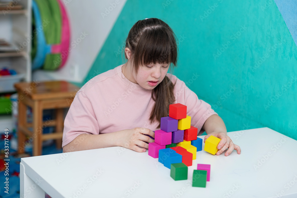 Sunny girl playing colored cubes in the educational room. World day of people with down syndrome. A special child Sunny girl playing colored cubes in the educational room. World day of people with down syndrome. A special child