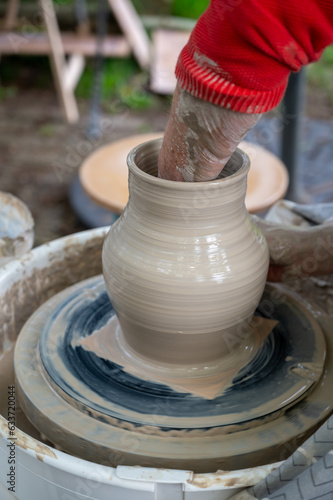 Making of mud pot on potters wheel during workshop outdoor © barmalini