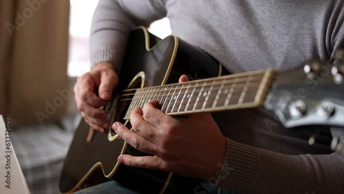 Playing the guitar. Strumming acoustic guitar. Musician plays music. Man fingers holding mediator. Man hand playing guitar neck in dark room. Unrecognizable person rehearsing, fretboard close-up.	
