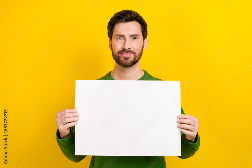Photo of confident man patriot wear green trendy sweatshirt arm hold placard stop war show blank space isolated on yellow color background Photo of confident man patriot wear green trendy sweatshirt arm hold placard stop war show blank space isolated on yellow color background