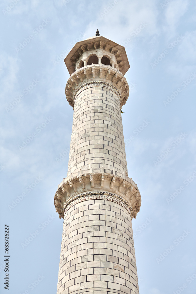 Minaret of Taj Mahal white marble mausoleum landmark in Agra, Uttar Pradesh, India, beautiful white tower adjacent to ancient Taj Mahal tomb building, popular touristic place with Mughal architecture