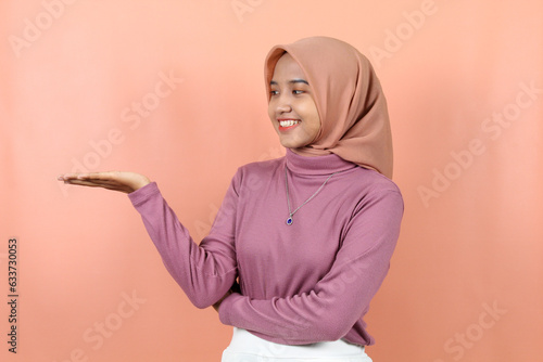 Asian woman pointing at the copy space © Miftakhul Fariz