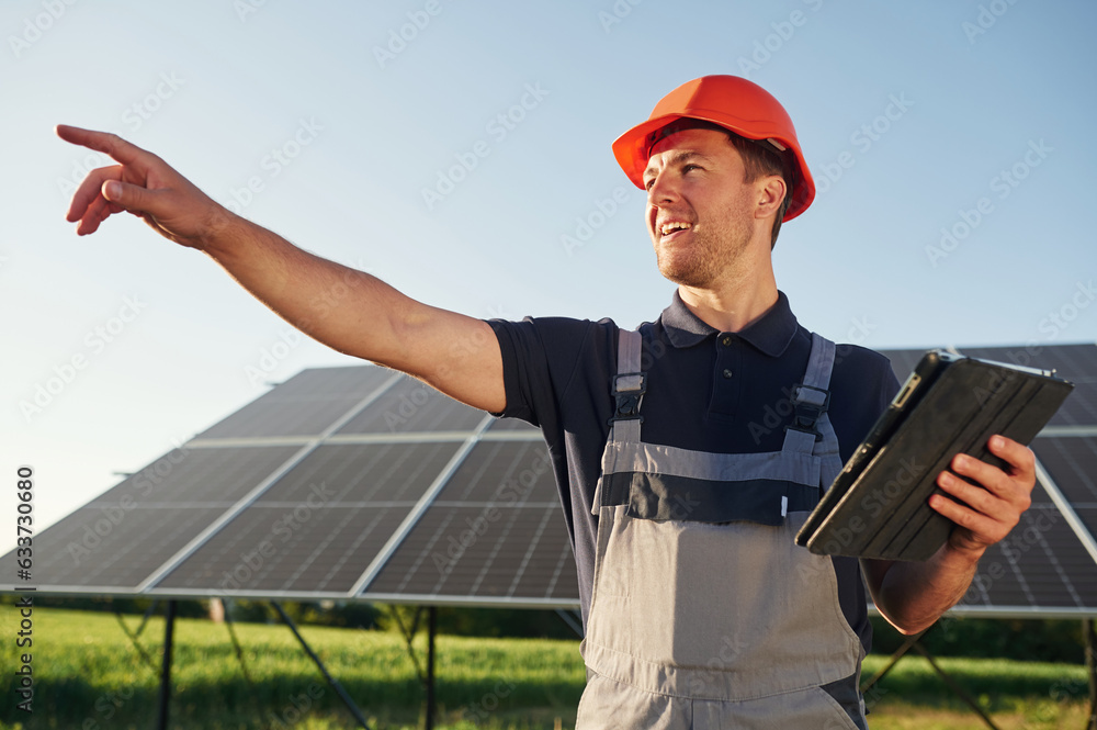 Summer time, standing and holding digital tablet. Man is doing operating and maintenance in solar power plant