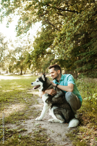 Handsome young man sitting with his dog in the park.