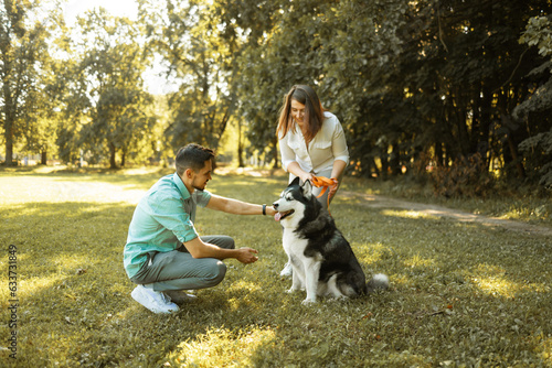 Young couple with husky dog in park on sunny day. Love concept