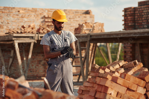 Wearing the gloves. Handsome Indian man is on the construction site