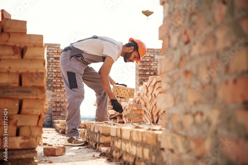 Side view, working and placing the bricks. Handsome Indian man is on the construction site