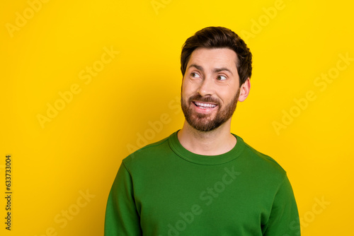 Portrait of funny bearded guy toothy smile look side empty space adv ad wearing green sweatshirt isolated yellow color background