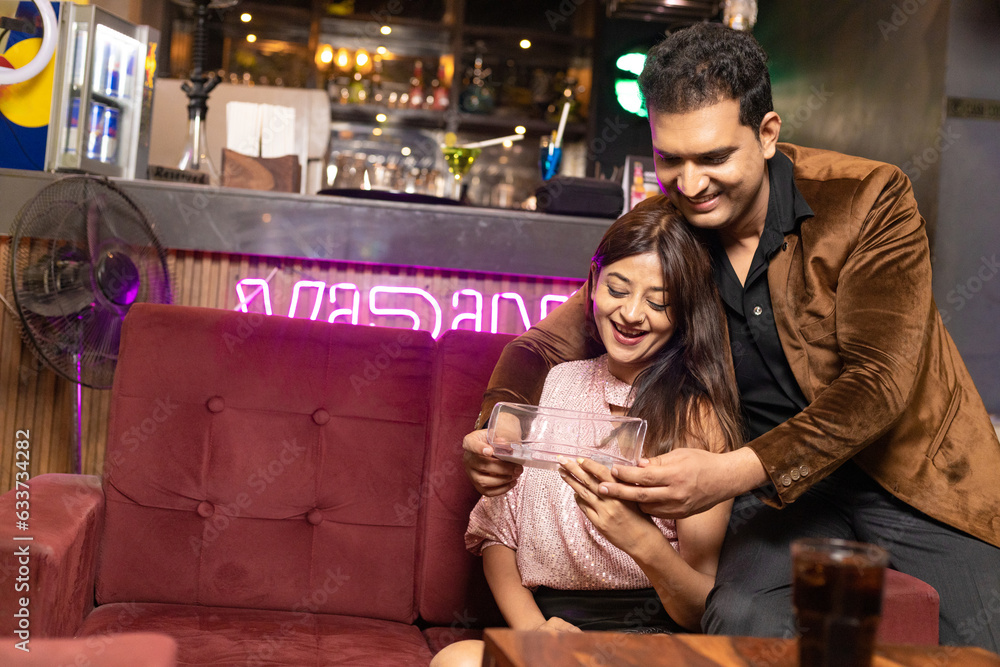 Indian man giving gift to his girl friend or wife at restaurant Indian man giving gift to his girl friend or wife at restaurant