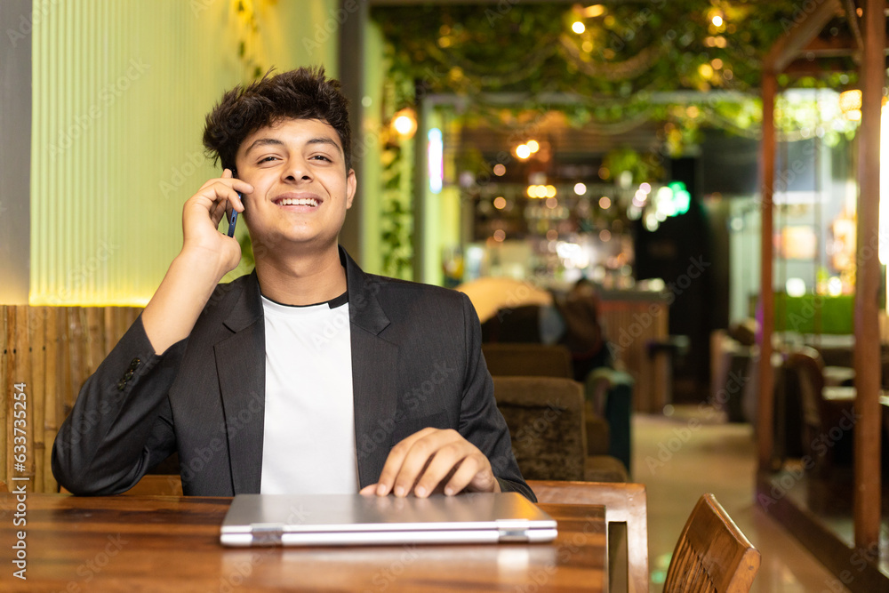 Young indian boy talking on smartphone at restaurant. Young indian boy talking on smartphone at restaurant.