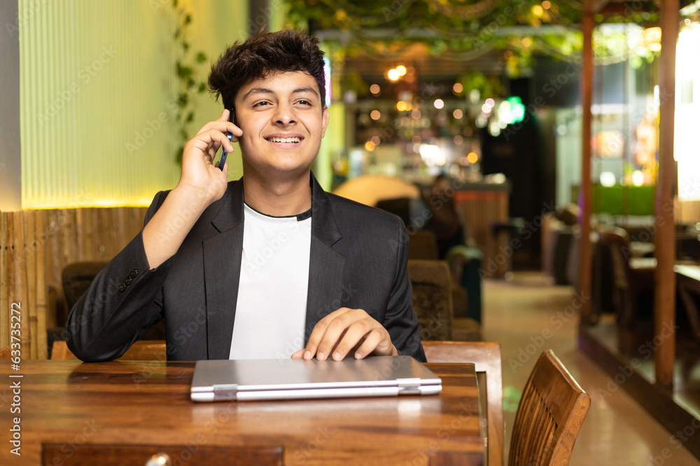 Young indian boy talking on smartphone at restaurant. Young indian boy talking on smartphone at restaurant.