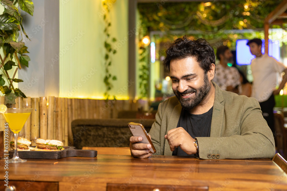 Indian man using smartphone at restaurant Indian man using smartphone at restaurant