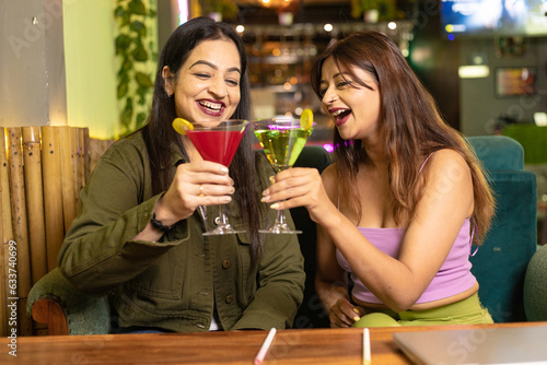 Two indian female friends enjoying cold drinks together at restaurant