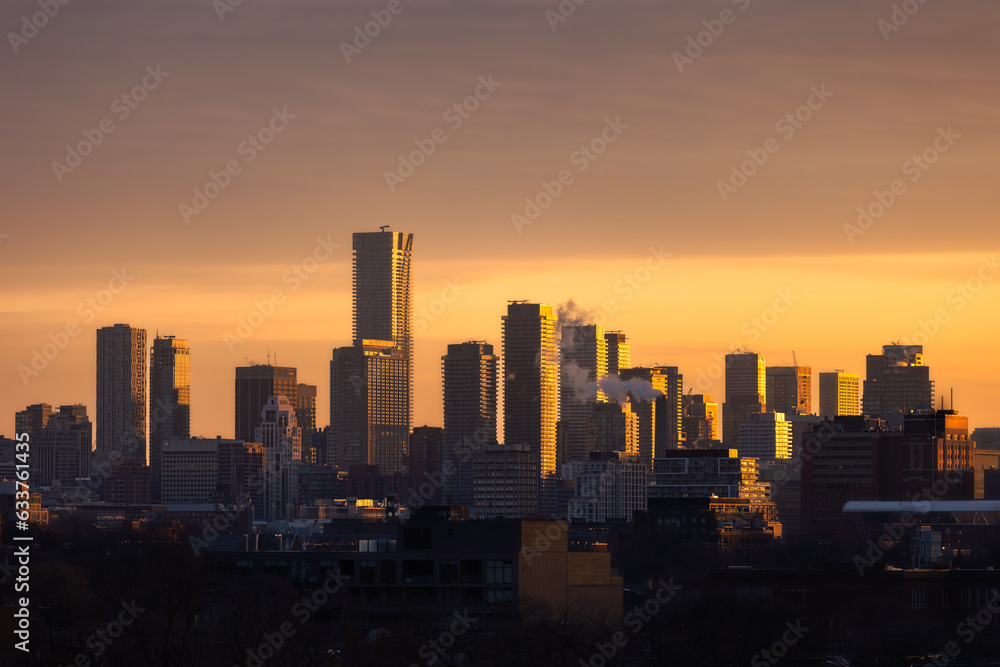 Downtown Toronto skyline at sunrise, with golden light illuminating the sky and sides of buildings