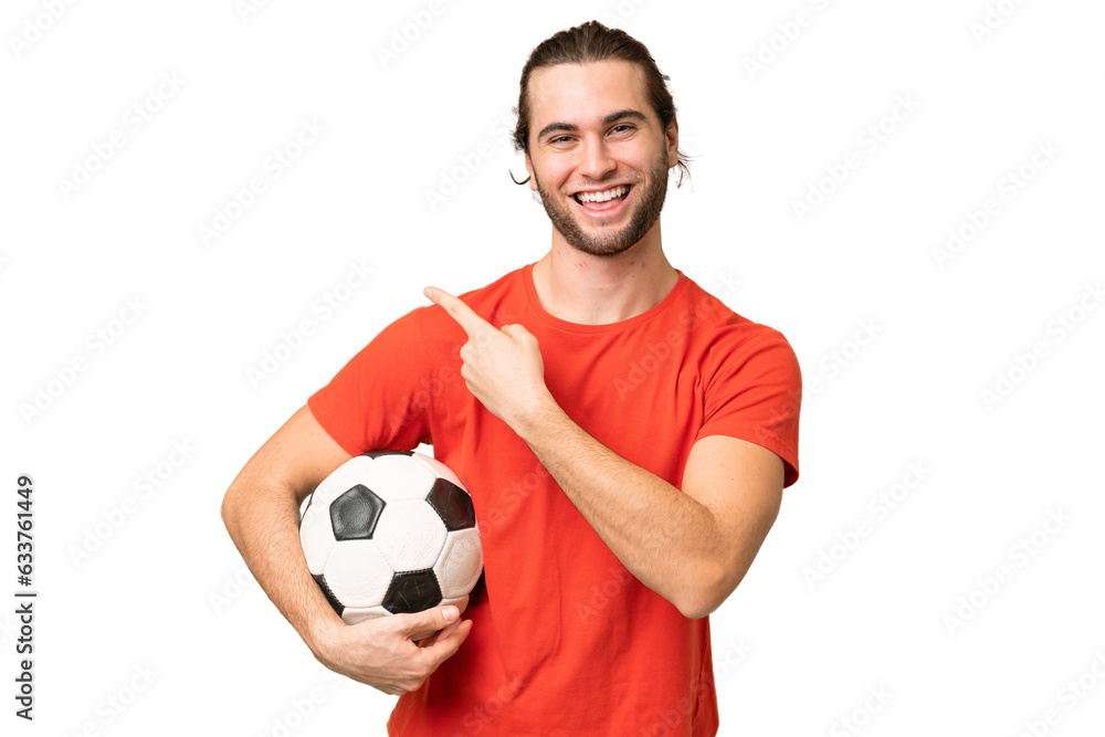 Young handsome man isolated on green chroma background with soccer ball and pointing to the lateral