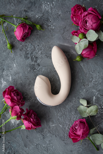 Adult toy on a concrete background with pink flowers