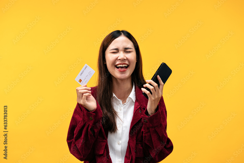 Young asian woman wearing red jacket and big smiling while holding smartphone and new credit card for online Young asian woman wearing red jacket and big smiling while holding smartphone and new credit card for online