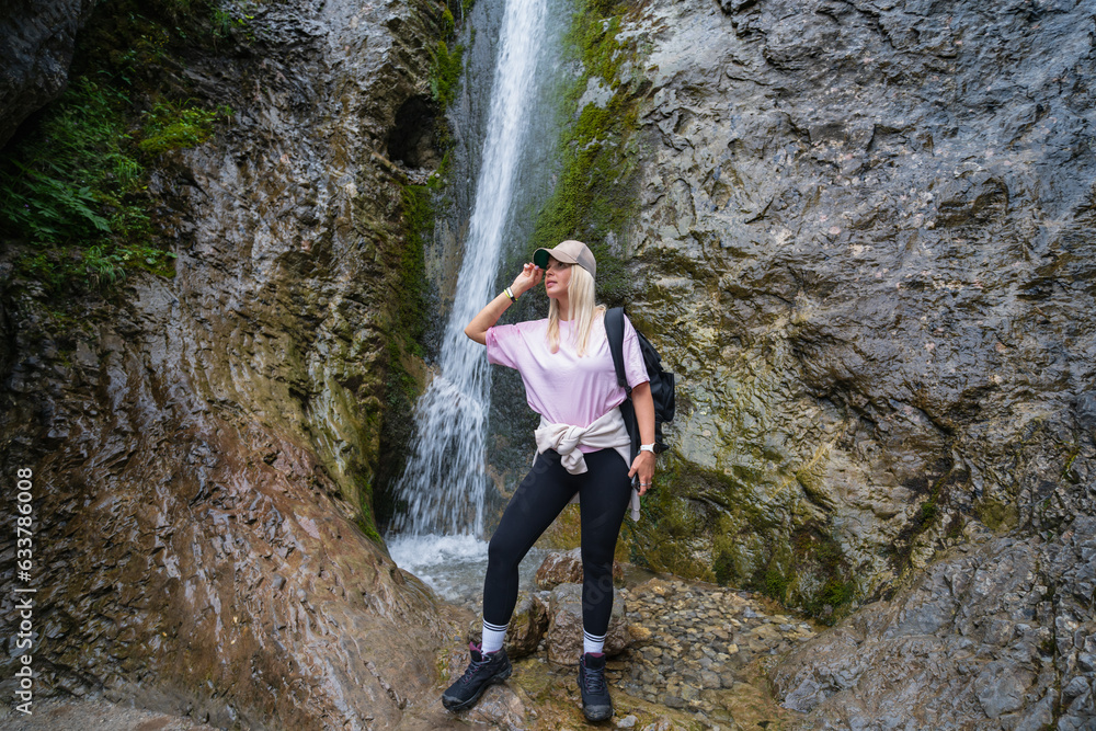 Girl trekker in the Tatra mountains at the Siklawica waterfall in summer.