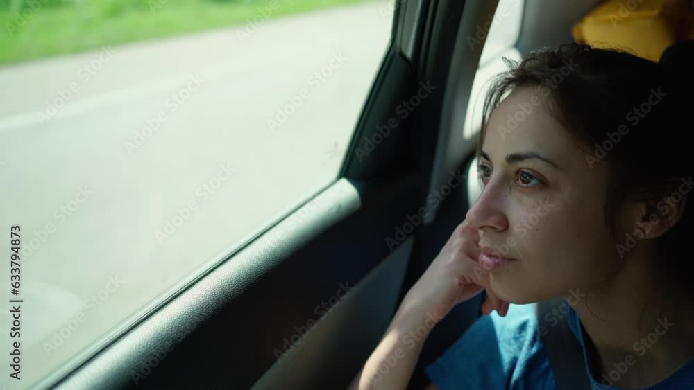 young woman sitting close to window in moving car and looking outside. girl is bored during long road trip in summer in car. summertime vacation car traveling young woman sitting close to window in moving car and looking outside. girl is bored during long road trip in summer in car. summertime vacation car traveling