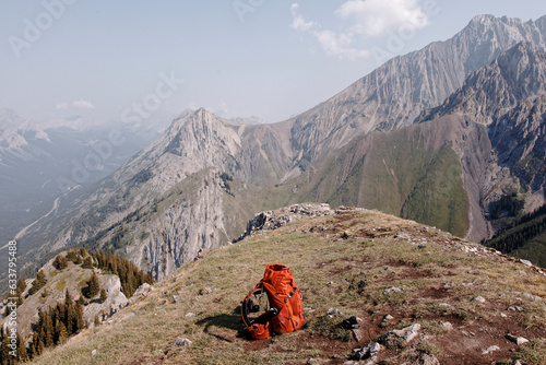 Views of Mountains and Cloudy Blue Skies in Kananaskis Country Alberta on a Summer Day with an Orange Backpack proppedup on some grass