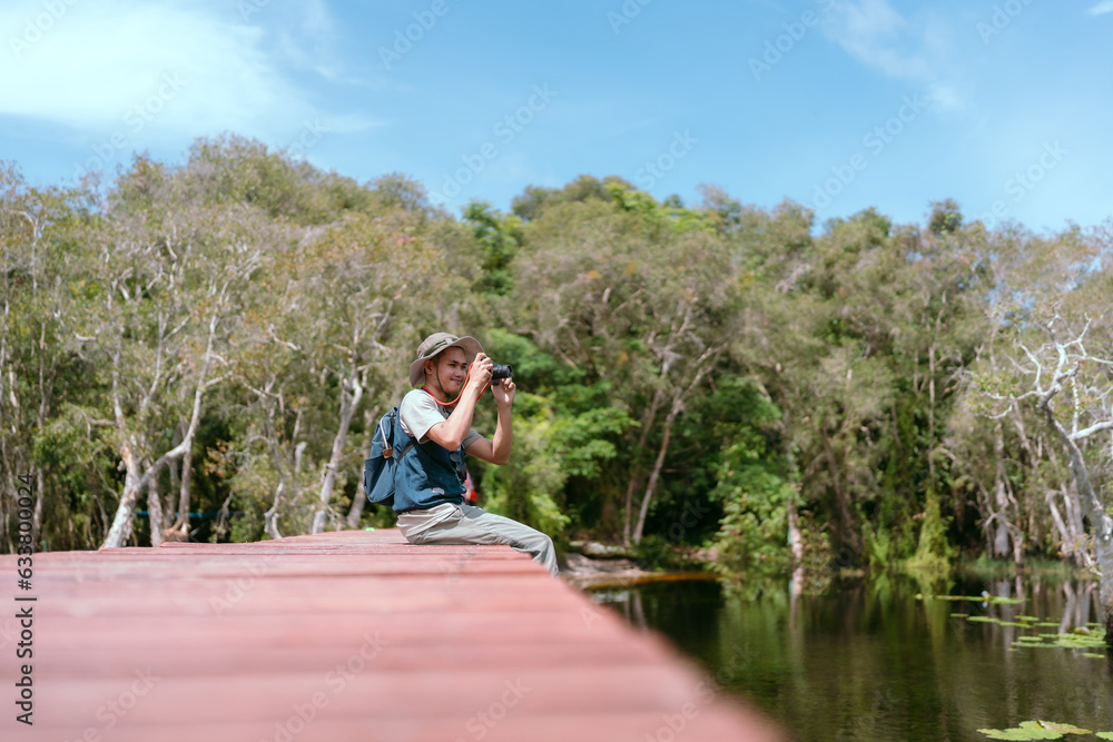 Asian man sitting and traveling on a bridge Take fun photos and videos. Rivers and mangroves