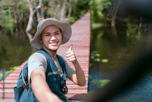 Asian man walking on a bridge filming a cheerful live video in mangrove forests and rivers