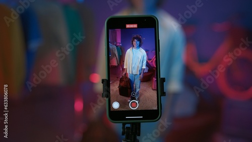 Smartphone display, man demonstrates new backpack in front of the camera and filming a video for social networks at home.