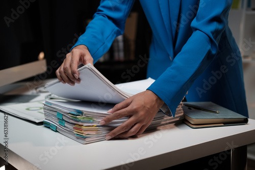 Asian businesswoman searching scattered piles of documents in the office