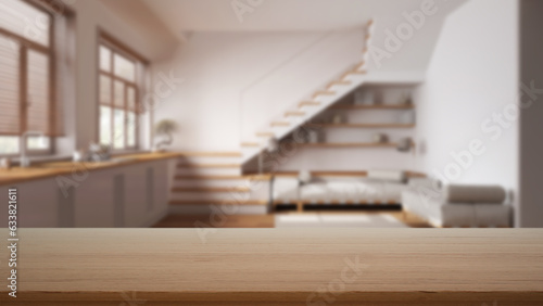 Empty wooden table, desk or shelf with blurred view of minimal white kitchen and living room with sofa and staircase, modern interior design concept