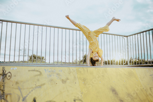 Mädchen, 9 Jahre, im gelbweiß gestreiften Jumpsuit schlägt ein Rad