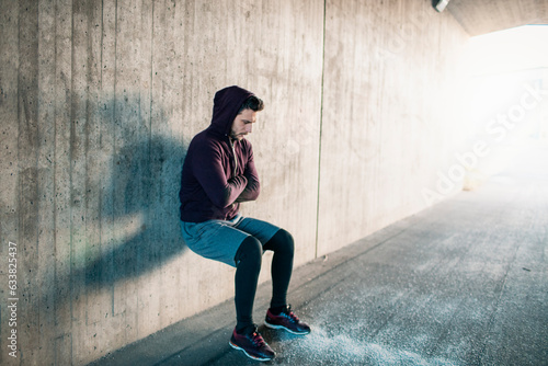 Young man stretching and warming up before jogging and exercising in a tunnel underpass