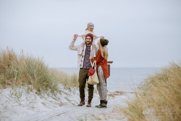 Young family walking on a beach during winter