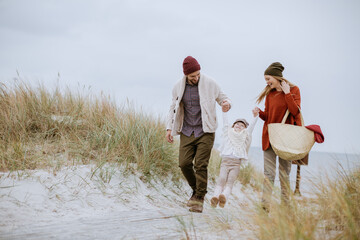 Young family walking on a beach during winter