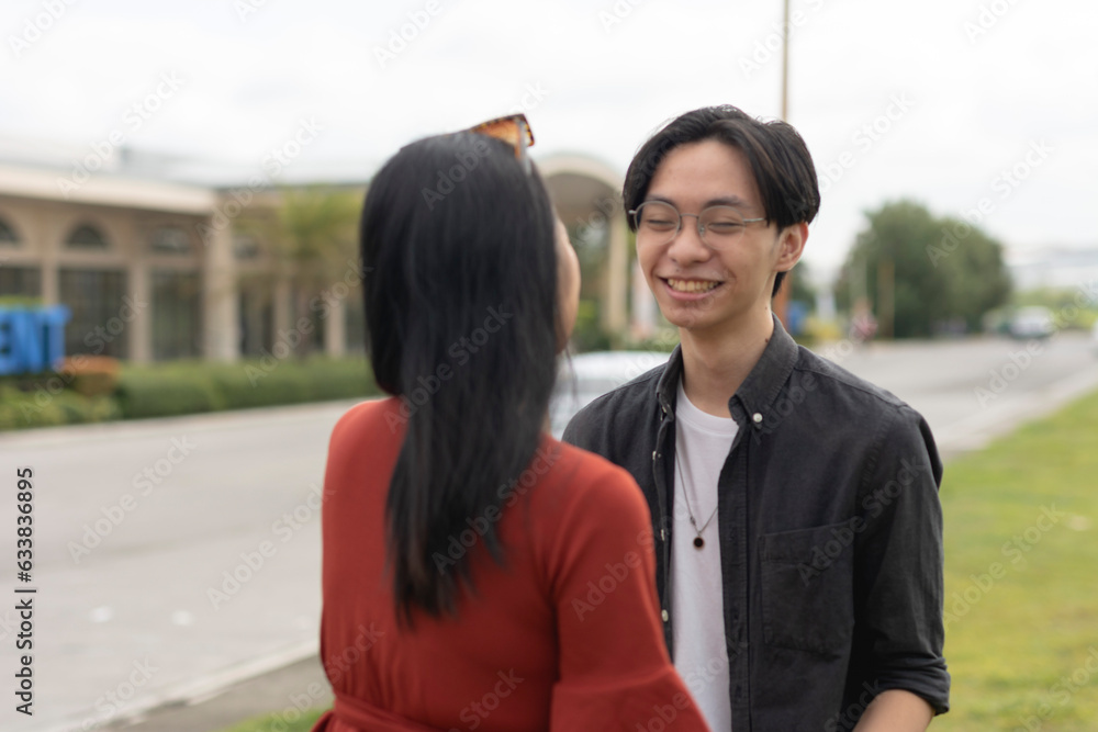 A young affectionate asian couple enjoy a nice chat while looking at each other's eyes and smiling. A public display of affection. A young affectionate asian couple enjoy a nice chat while looking at each other's eyes and smiling. A public display of affection.