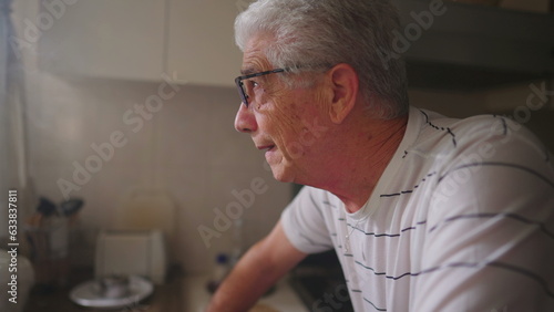 Senior Man in Moment of Hope, Looking Upwards Towards Window at Home, standing in kitchen. Faithful person