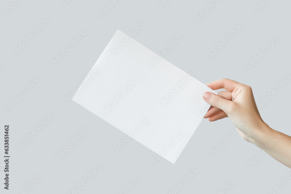 female hand holding blank white a5 poster isolated on gray background female hand holding blank white a5 poster isolated on gray background