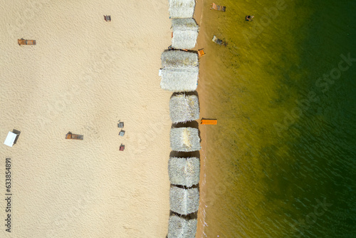 Aerial view of palm-thatched beach huts at Pindobal, a freshwater beach on the banks of the Tapajos river in Belterra, Para, Brazil.