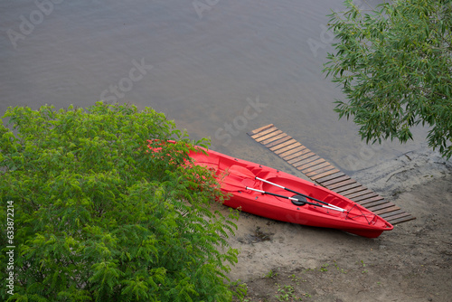 A red kayak on the river bank