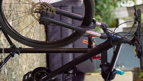 Vertical video Modern bicycle is visible in the yard positioned on repair-stand for examining and mending. Outdoor various bike components await adjustments and restoration with professional work photo